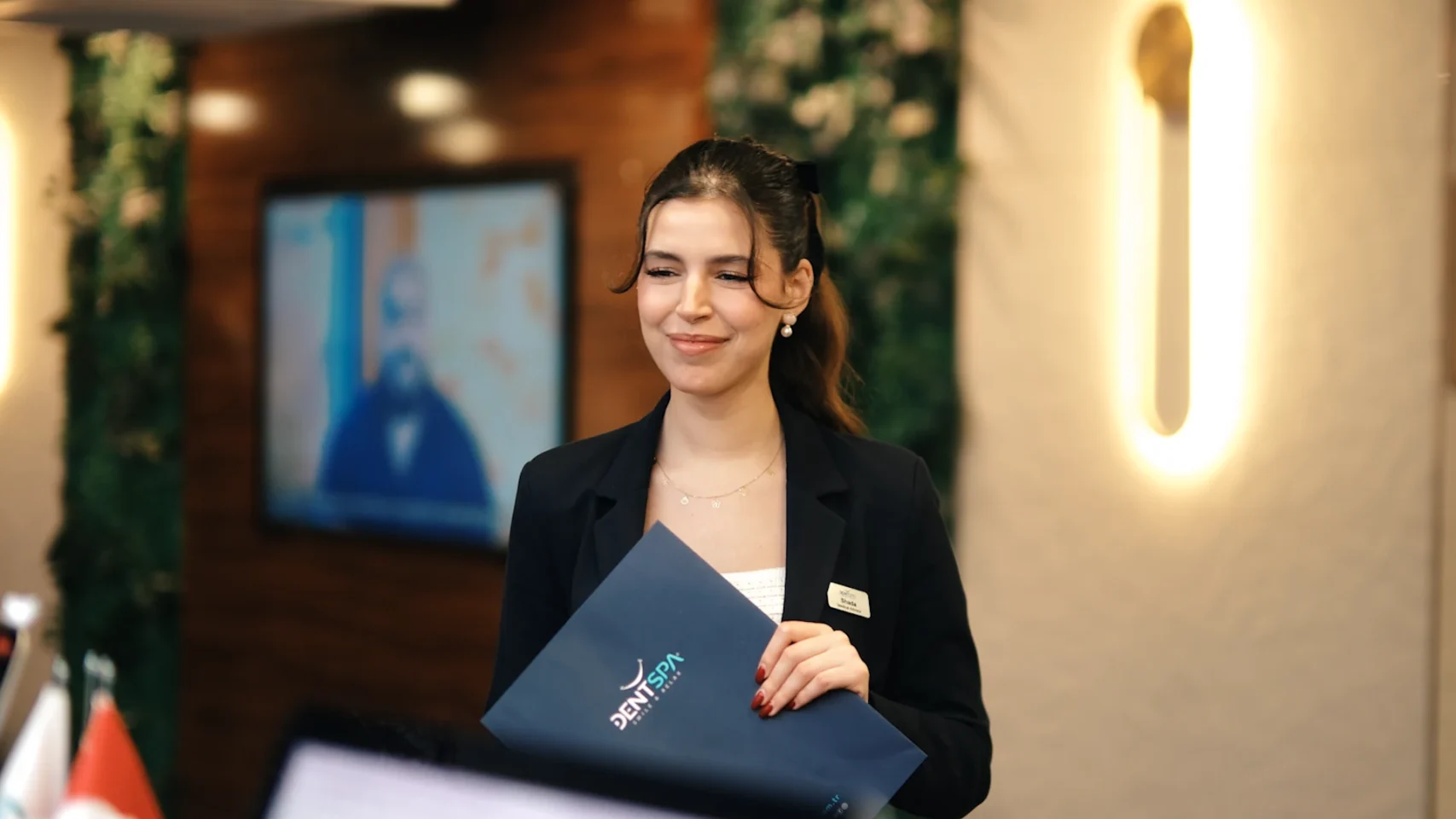 A DentSpa patient coordinator holding a welcome folder at the clinic reception